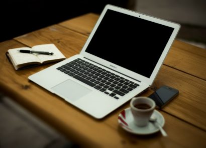 Coffee, notebook and laptop computer on a wood desk