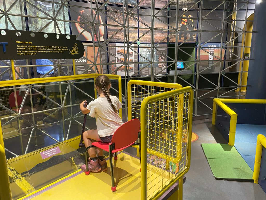 Girl working a play excavator inside the Play Lab at the Oil Sands Discovery Centre