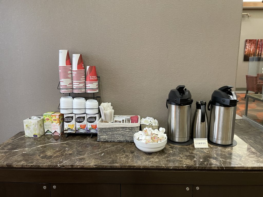 Coffee station in the lobby of Radisson Hotel and Suites Fort McMurray with cups, tea, hot chocolate, sugar, splenda, and coffee mate.
