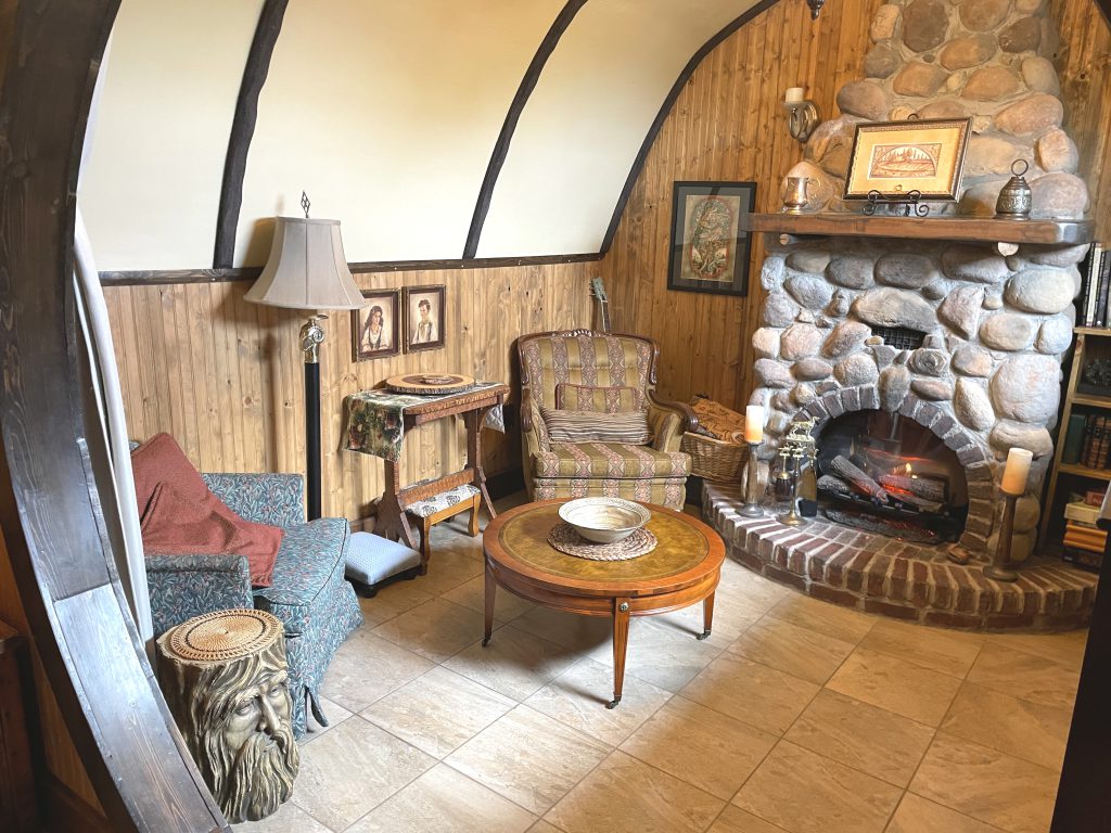 The living room in The Burrow showing both chairs, the coffee table, and fireplace. 