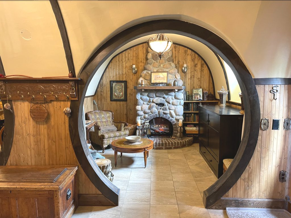 The Burrow's living room through the round doorway next to the front entrance. The electric fireplace is lit, and it is super welcoming and cozy.